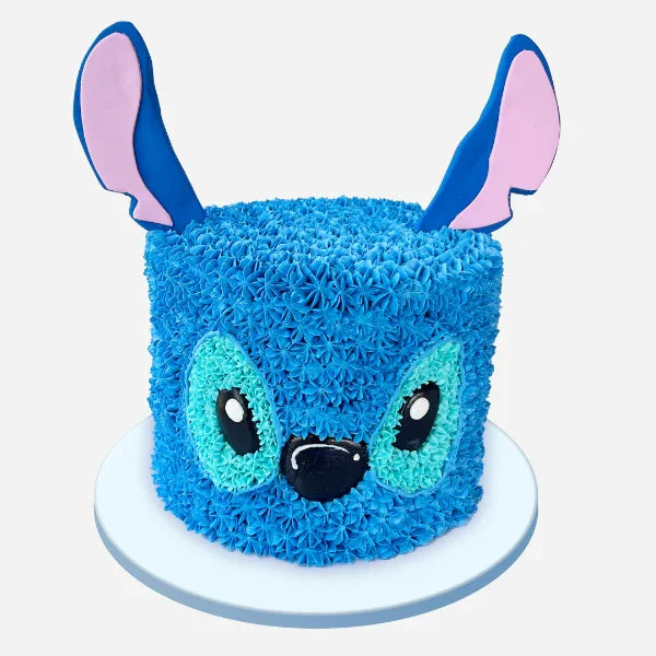 Blue cake shaped like a cartoon character with pink ears on a white background